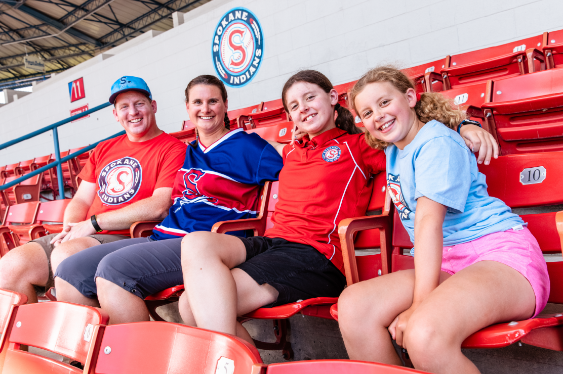 Photo of a family of four in the stands at a baseball game