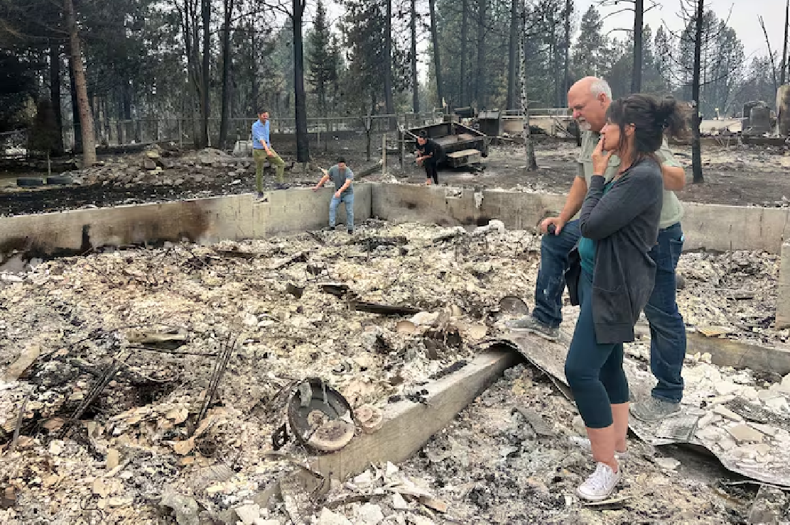Photo of a couple standing in the remains of a burned down house